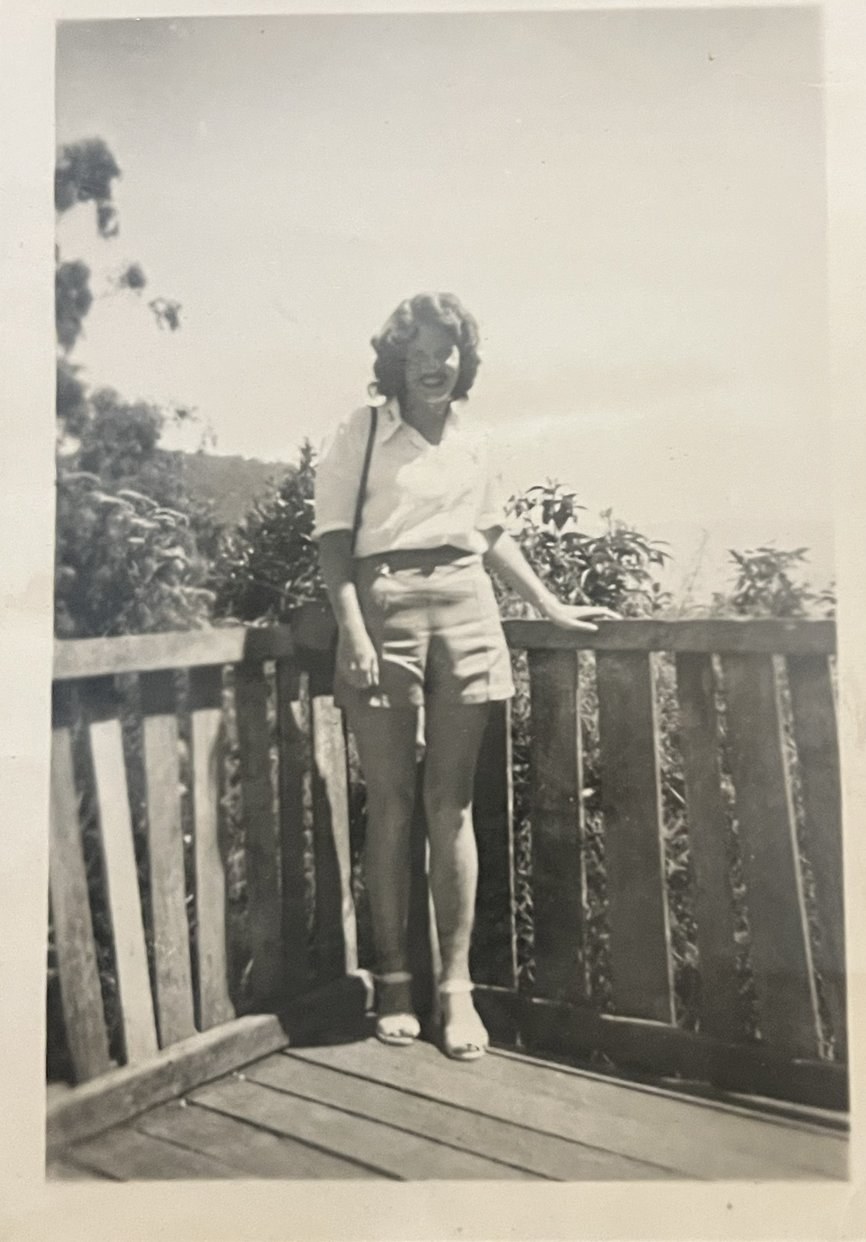 Lois as a young woman, standing on a timber verandah — an old family photograph