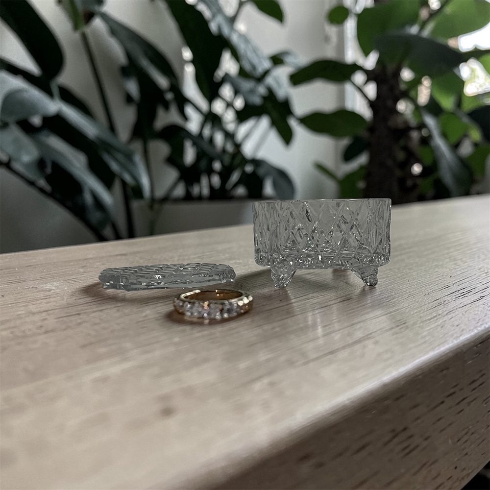 Cut glass canister holding a gold ring on a timber table